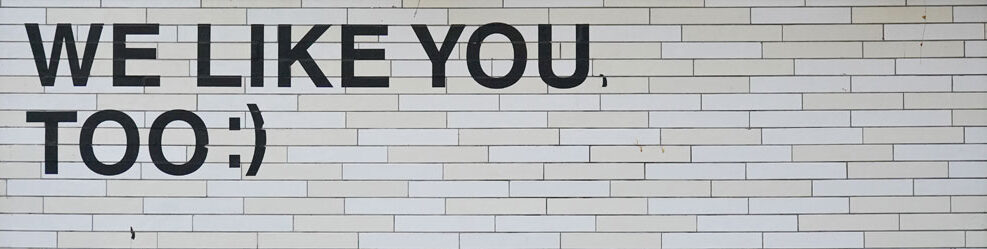 Weiße Mauer mit aufgedrucktem Schriftzug "We like you, too :)"